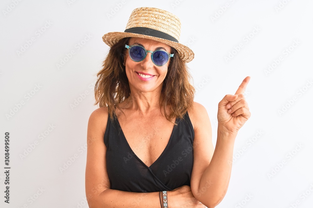 Middle age woman wearing black t-shirt sunglasses and hat over isolated white background very happy pointing with hand and finger to the side Middle age woman wearing black t-shirt sunglasses and hat over isolated white background very happy pointing with hand and finger to the side