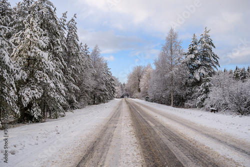 car tracks in the snow on the winter road in sunny day