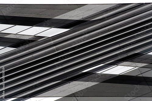 Low angle view of gray steel wall panels with slots. Fragment of industrial building exterior. Abstract modern architecture background with geometric structure. Parallel lines in diagonal composition.