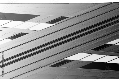 Low angle view of gray steel wall panels with slots. Fragment of industrial building exterior. Abstract modern architecture background with geometric structure. Parallel lines in diagonal composition.