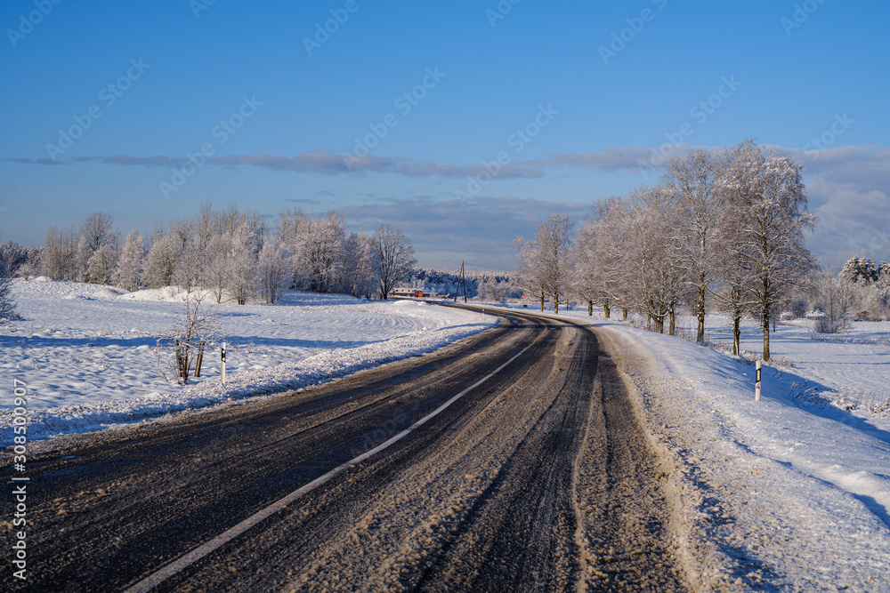 car tracks in the snow on the winter road in sunny day