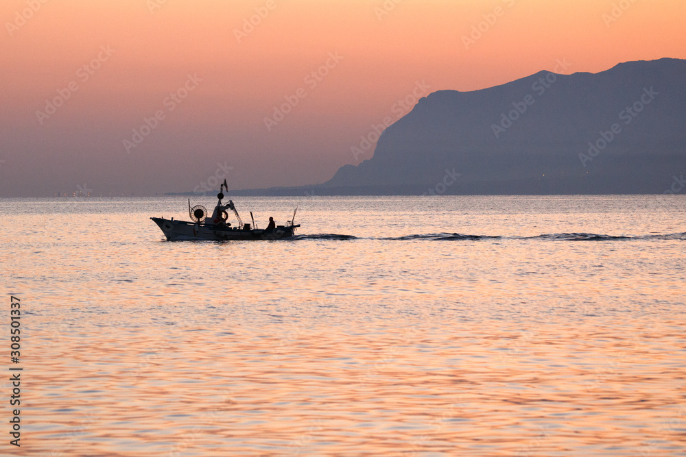 at dawn, a fishing boat goes out to sea. EDITORIAL USE ONLY