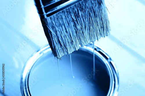 Fototapeta Naklejka Na Ścianę i Meble -  Blue paint is dripping from brush into open can on freshly painted wooden background. Renovation concept. Macro.