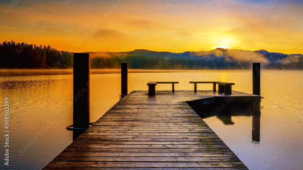 Sunrise over lake with with pier and orange sky