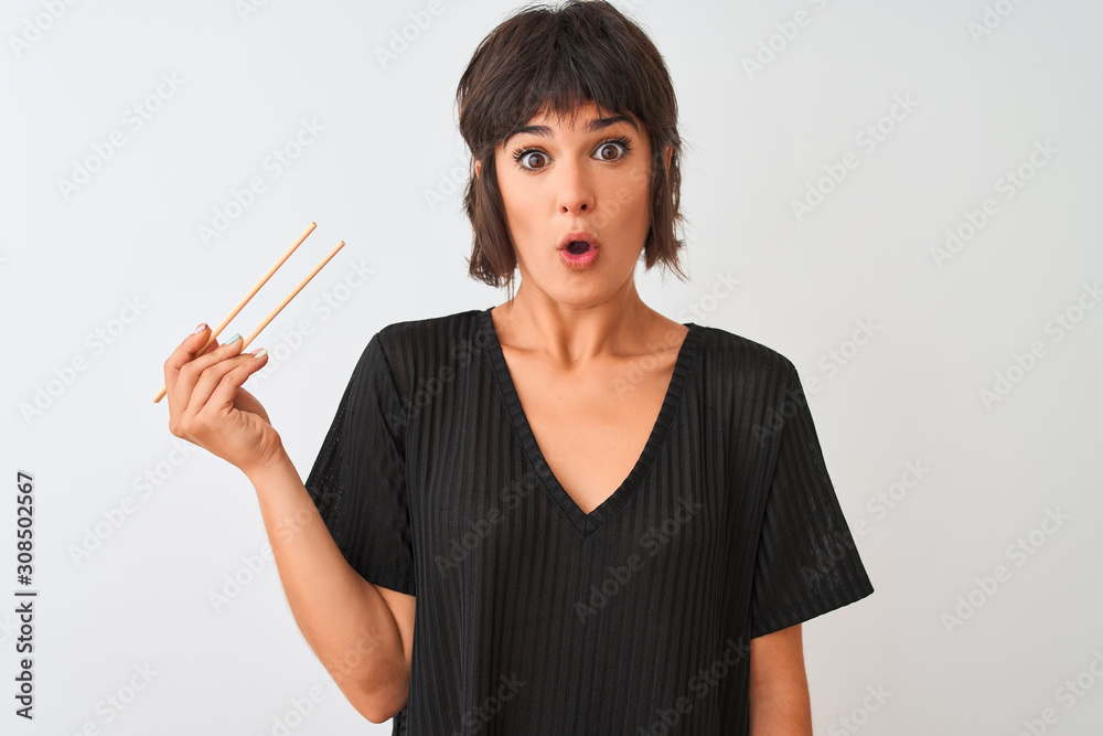 Young beautiful woman holding chopsticks standing over isolated white background scared in shock with a surprise face, afraid and excited with fear expression Young beautiful woman holding chopsticks standing over isolated white background scared in shock with a surprise face, afraid and excited with fear expression