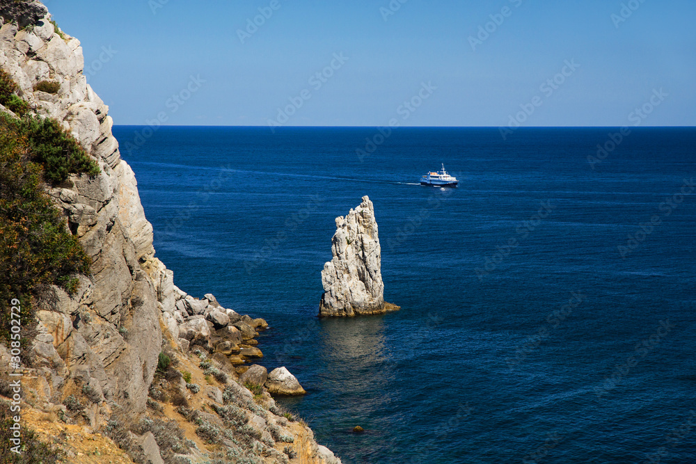 Black Sea view with Rock Formation in the shape of a sail and a white cruise ship in the distance. Crimea, Ukraine