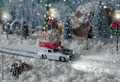 Miniature classic car carrying a christmas gifts on snowy winter landscape