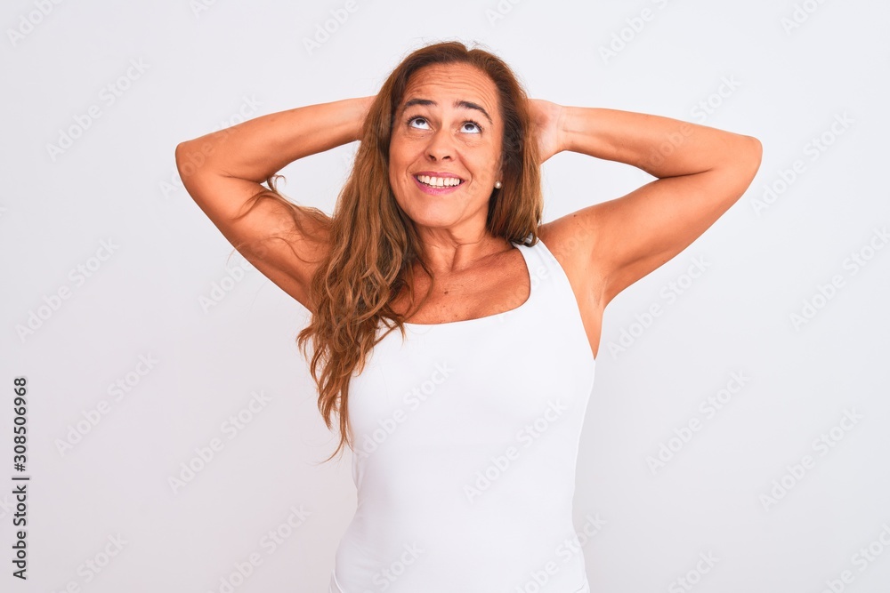 Middle age mature woman standing over white isolated background relaxing and stretching, arms and hands behind head and neck smiling happy Middle age mature woman standing over white isolated background relaxing and stretching, arms and hands behind head and neck smiling happy