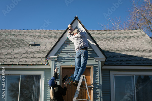 Wallpaper Mural Couple hanging Christmas lights on peak of house Torontodigital.ca
