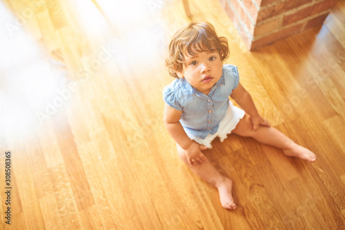 Beautiful toddler child girl wearing blue denim shirt sitting on the floor