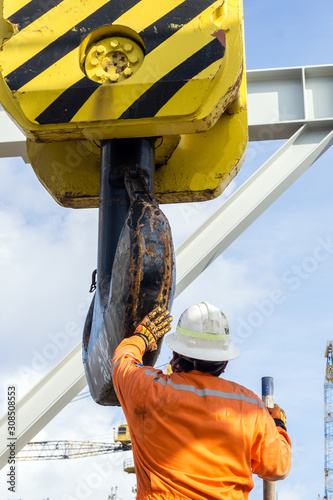 Offshore worker performing inspection to a crane block prio to heavey lifting works on board a construction work barge at oil field