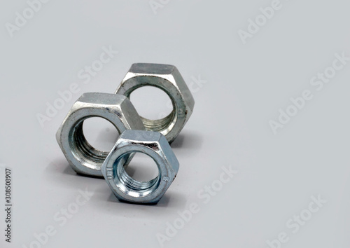 Metal nuts isolated on gray background. New and shiny chrome nuts. Copy space.