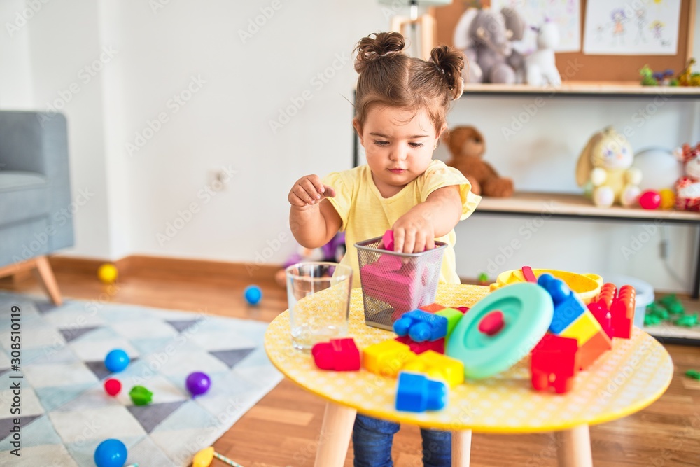 Beautiful toddler playing with building wooden blocks toys at kindergarten Beautiful toddler playing with building wooden blocks toys at kindergarten