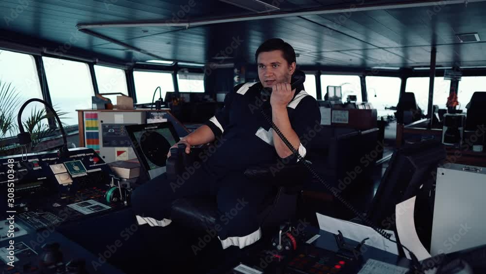 Marine Deck Officer or seaman on navigation bridge of vessel or ship . He is speaking on the VHF radio. Colreg communication Marine Deck Officer or seaman on navigation bridge of vessel or ship . He is speaking on the VHF radio. Colreg communication