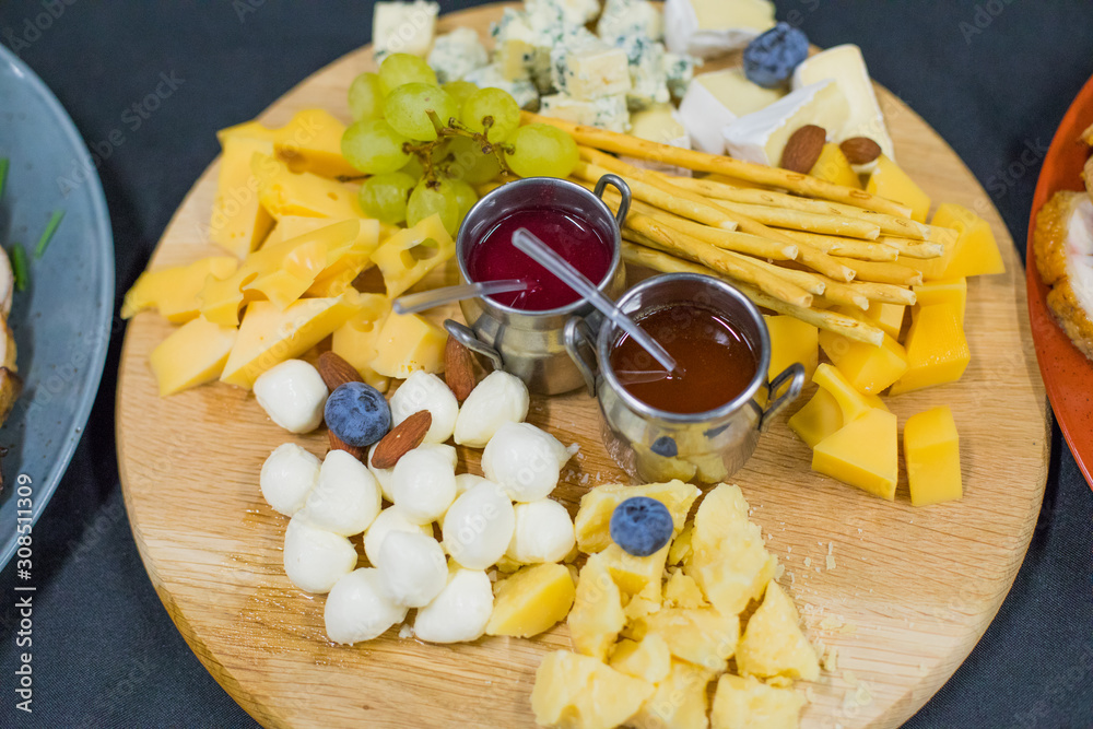 Cheese plate: Parmesan, cheddar, gouda, mozzarella and grapes and berry sauce. Tasty appetizers.  Top view