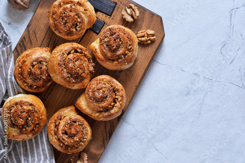 Snail buns with cinnamon and nuts on a concrete background.