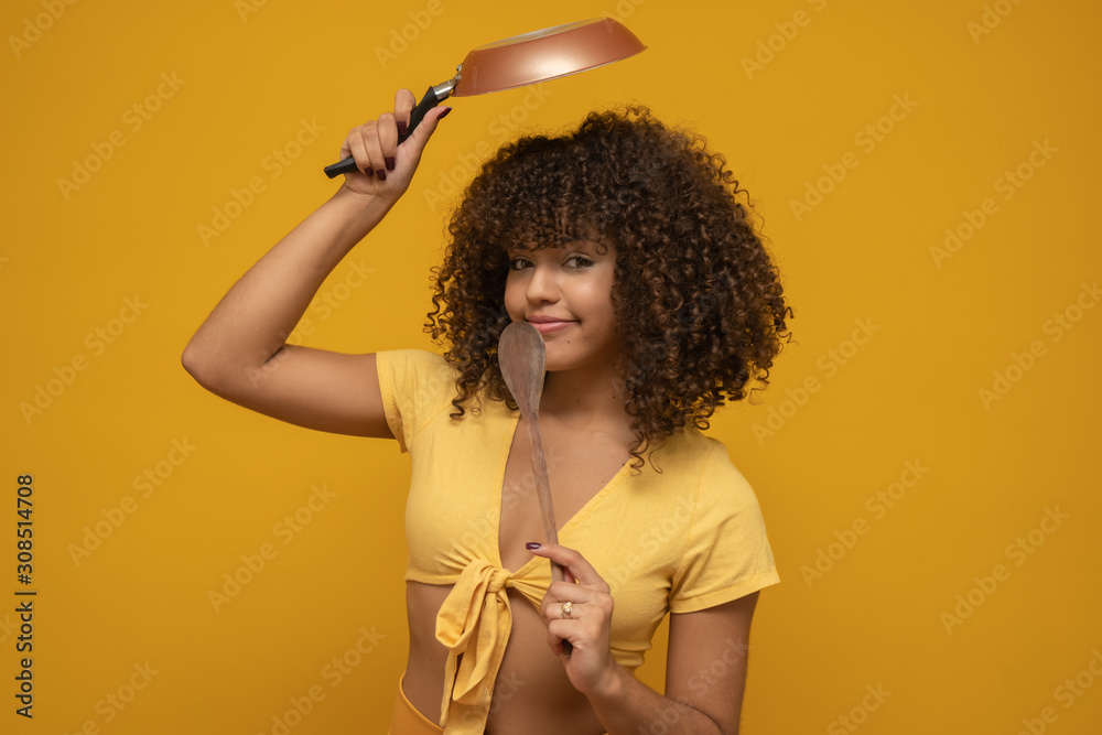 Cooking utensils. Cooking woman in kitchen with frying pan and wooden  spoon. Housewife dancing. Stock Photo