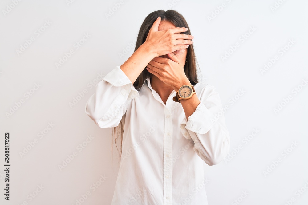 Young beautiful businesswoman wearing glasses standing over isolated white background Covering eyes and mouth with hands, surprised and shocked. Hiding emotion Young beautiful businesswoman wearing glasses standing over isolated white background Covering eyes and mouth with hands, surprised and shocked. Hiding emotion
