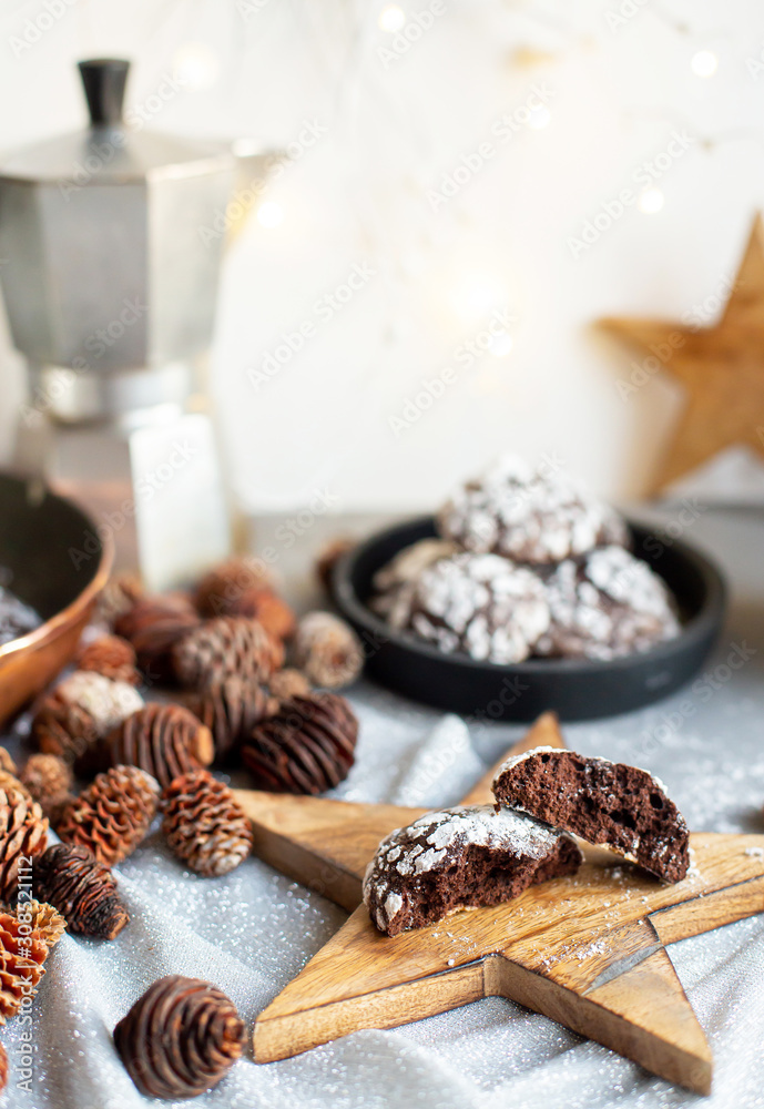 Home baked chocolate crinkle cookies in icing sugar. Cracked chocolate biscuits in a white plate on Christmas background. Chocolate Christmas brown cookies in powdered sugar with cracks. Copy space. Home baked chocolate crinkle cookies in icing sugar. Cracked chocolate biscuits in a white plate on Christmas background. Chocolate Christmas brown cookies in powdered sugar with cracks. Copy space.