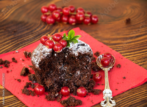 halbes schokoladenmuffin mit puderzucker und johannisbeeren dekoriert photo