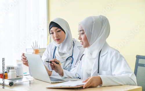 Two woman muslim doctors using a digital tablet, discussing diagnosis deadly disease in Specialized clinics