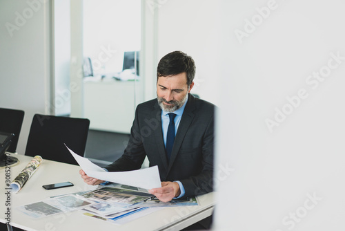 Mature businessman working on photographies at desk in office