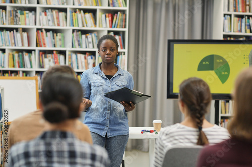 African young speaker presenting business strategy to young people at presentation in the library