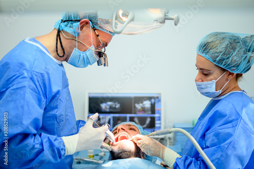Dental surgeon and assistant work putting dental implant photo
