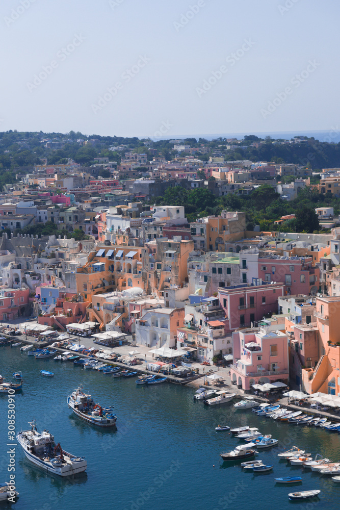Panoramic view of beautiful Procida on a sunny summer day. Colorful cafes, houses and restaurants, fishing boats and yachts, clear blue sky and the azure sea on the island of Procida, Italy. Napoli
