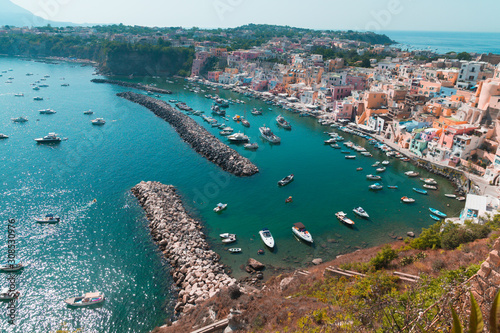 Panoramic view of beautiful Procida on a sunny summer day. Colorful cafes, houses and restaurants, fishing boats and yachts, clear blue sky and the azure sea on the island of Procida, Italy. Napoli
