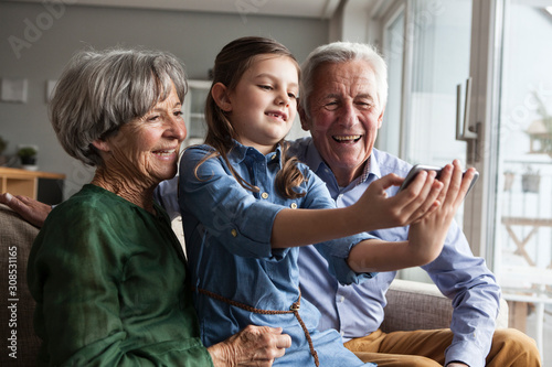 Little girl taking selfie with her grandparents at home photo