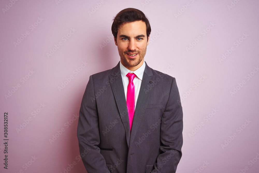 Young handsome businessman wearing suit and tie standing over isolated pink background with a happy and cool smile on face. Lucky person. Young handsome businessman wearing suit and tie standing over isolated pink background with a happy and cool smile on face. Lucky person.