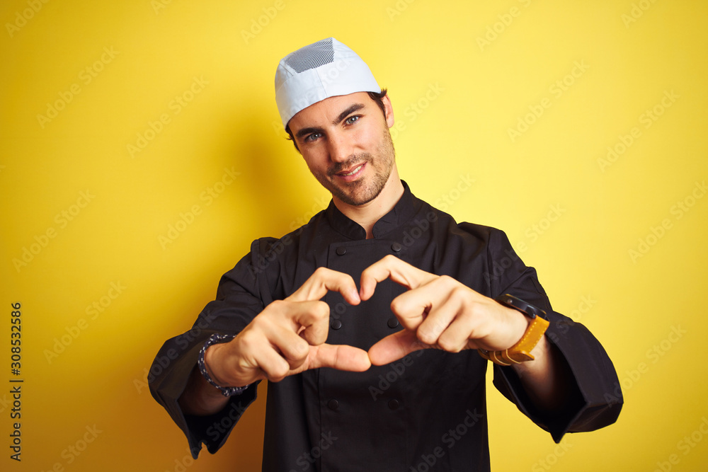 Young handsome chef man cooking wearing uniform and hat over isolated yellow background smiling in love showing heart symbol and shape with hands. Romantic concept. Young handsome chef man cooking wearing uniform and hat over isolated yellow background smiling in love showing heart symbol and shape with hands. Romantic concept.
