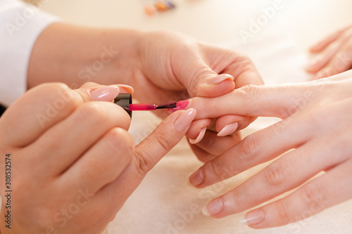 Medicine  cosmetology and manicure. Manicure with painting nails in color pink nail Polish. Hands close up