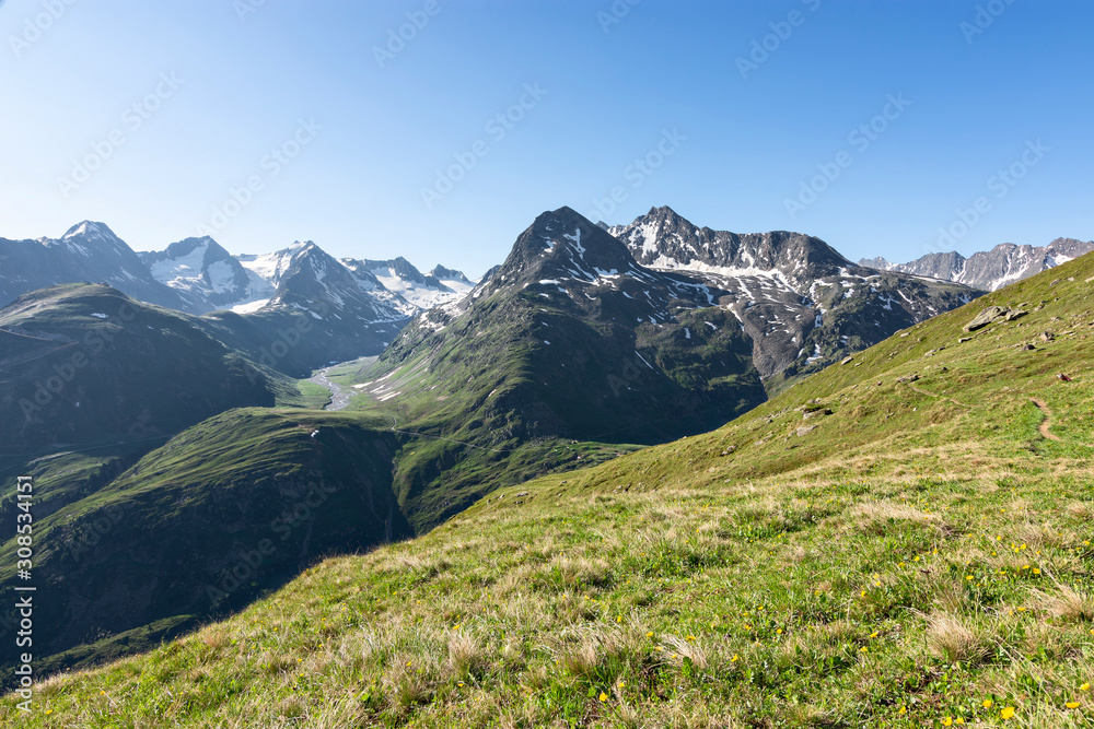 Alpine landscape in summer with rocky mountains, glaciers and green pastures under blue sky. Oetztal Alps, Tirol, Austria.