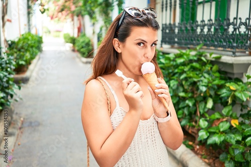 Young beautiful woman eating ice cream cone on a sunny day of summer on holidays