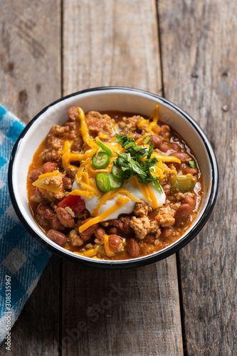 Texmex dish called "Chili con carne" with cheese and sour cream on wooden background