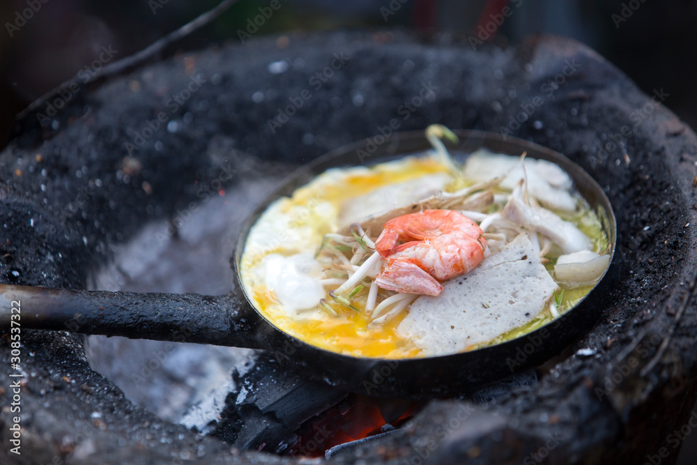 Close up of Vietnamese pancake with egg and shrimp cooking in pan. Close up of Vietnamese pancake with egg and shrimp cooking in pan.