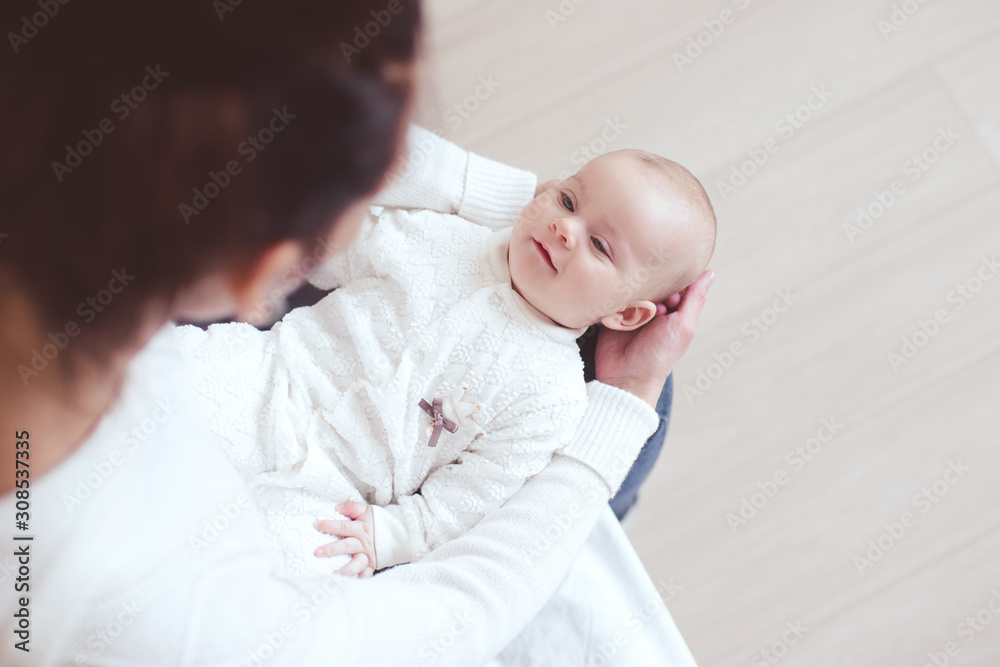 Happy baby 1 year old lying on mother hands in room. Looking at each other. Maternity. Motherhood. Happy baby 1 year old lying on mother hands in room. Looking at each other. Maternity. Motherhood.