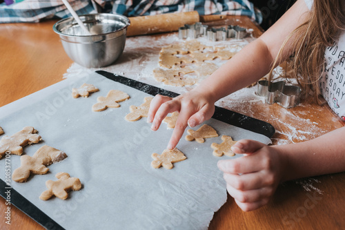 Young girl putting gingerbread man on baking tray photo