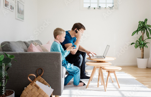 father sat at home with his son on his mobile and laptop photo