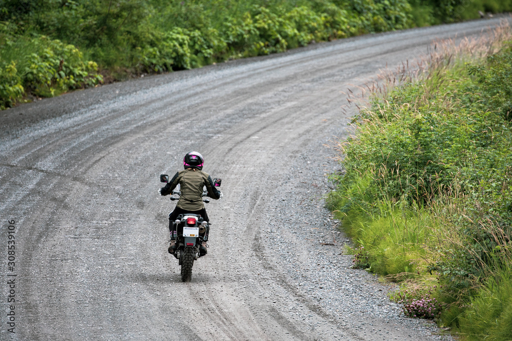 A women rides her motorcycle on a gravel road in Canada. A women rides her motorcycle on a gravel road in Canada.