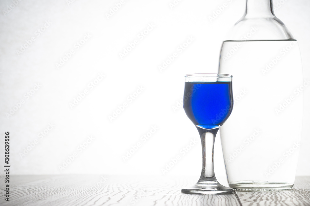 Obraz premium Glass bottle with vodka and a glass of blue cocktail
