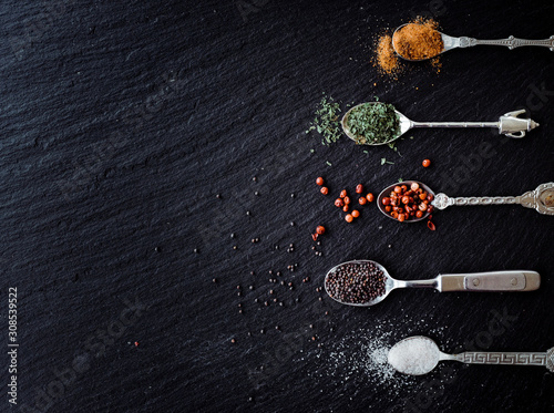 A selection of spices on vintage spoons on a slate chopping board photo