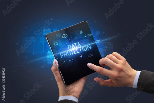 Businessman holding a foldable smartphone with DATA PROTECTION inscription, cyber security concept