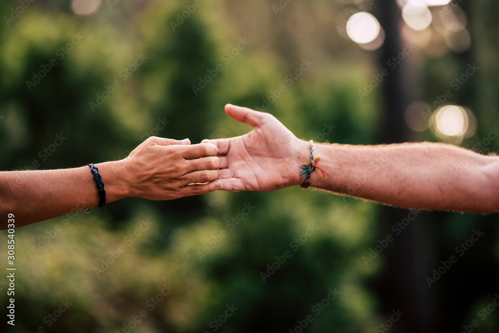 Close up of man and woman caucasian hands touching and holding with love and friendship - unrecognized people and green outdoor nature background - help and save forest concept