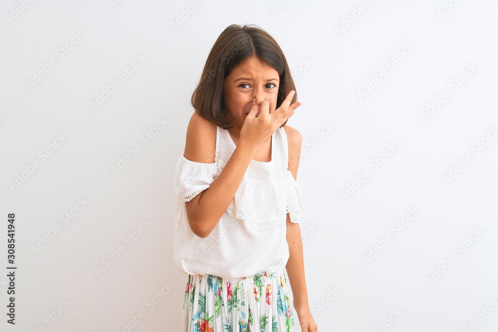 Young beautiful child girl wearing casual dress standing over isolated white background smelling something stinky and disgusting, intolerable smell, holding breath with fingers on nose. Bad smells Young beautiful child girl wearing casual dress standing over isolated white background smelling something stinky and disgusting, intolerable smell, holding breath with fingers on nose. Bad smells