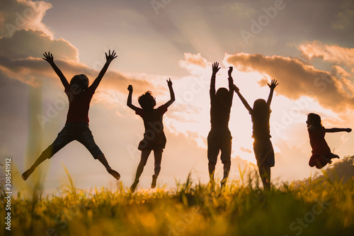 The silhouette of children jumping and playing happily in the mountains at sunset