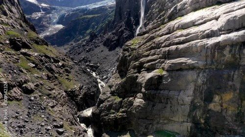 Aerial, drone shot, over the Glacier gorge, tiliting towards a waterfall and the Lower Grindelwald Glacier, on a sunny, summer day, in Bern, Switzerland photo