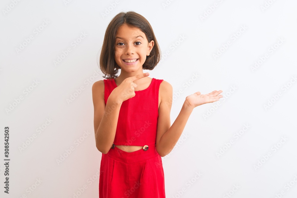 Young beautiful child girl wearing red casual dress standing over isolated white background amazed and smiling to the camera while presenting with hand and pointing with finger. Young beautiful child girl wearing red casual dress standing over isolated white background amazed and smiling to the camera while presenting with hand and pointing with finger.